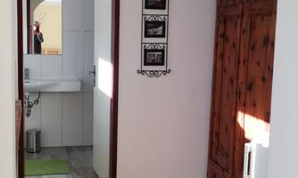 A bright corridor with an arch and wooden details. On the left side are picture frames and a door that leads into another room.