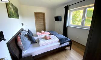 A bright bedroom with a double bed, equipped with comfortable pillows and blankets. A window offers a view of the outdoors and a pleasant atmosphere.
