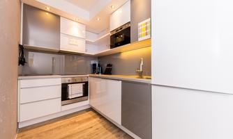 A modern kitchen with bright cabinets and an oven. The floor is made of wood and the lighting is warm and inviting.
