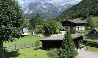 A picturesque landscape with mountains and green meadows. Traditional houses and trees harmoniously blend into nature.