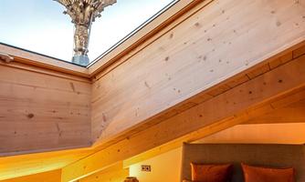 A cozy bedroom with wooden walls and a modern design. Through the skylight, a viewpoint is visible that shows the landscape.
