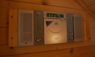 A CD player with radio and speakers is mounted on the wall. The device displays the time and has a modern, silver surface.