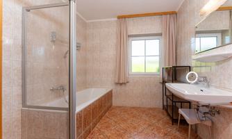 A modern bathroom with a shower and bathtub. Large windows provide plenty of daylight.
