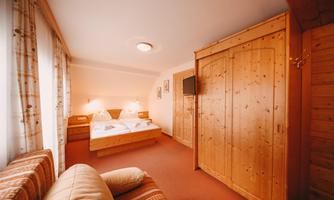 A cozy room with wooden furniture and a large bed. The room is brightly and pleasantly furnished.