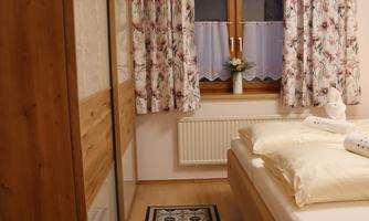A cozy bedroom with a wooden bed and a large window. The curtains and the carpet give the room a warm atmosphere.