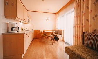 A bright, modern kitchen with wooden cabinets and a dining area. Large windows let in plenty of light and create an inviting atmosphere.