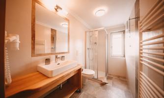 A modern bathroom with a shower cabin and an elegant sink. The walls are bright, and the decor is simple and functional.