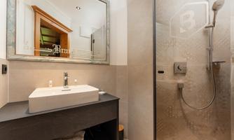 A modern bathroom with an elegant vanity top and a shower. The walls are in neutral tones and reflect a stylish decor.
