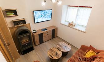 A cozy living space with wooden furniture, a television, and a fireplace. The atmosphere is warm and inviting.