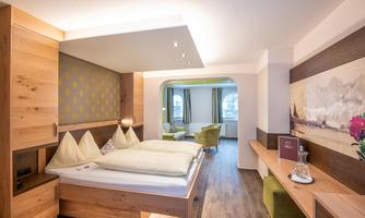 A modern bedroom with wood paneling and comfortable beds. The room is bright and friendly designed, with a cozy seating area.