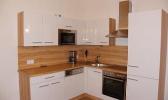 A modern kitchen with white cabinets and wooden details. The kitchen is well-equipped with a stove, oven, and microwave.