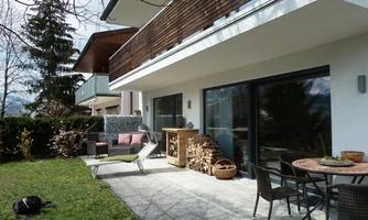 A modern house with a terrace and a garden. The furniture is stylish and the atmosphere is inviting.