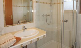 A modern bathroom with a shower cabin and a sink. Towels are ready and the room is bright and inviting.