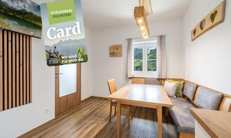 An inviting room with a large table and benches. A map with information about Schladming hangs on the wall.