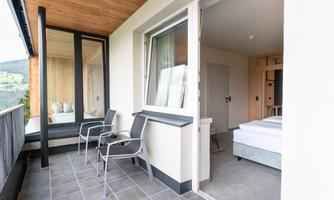 A modern balcony with two chairs and a view of a bright room. The surroundings convey a sense of tranquility and elegance.