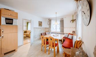A bright kitchen with an oak table and chairs. The room has large windows and an inviting atmosphere.