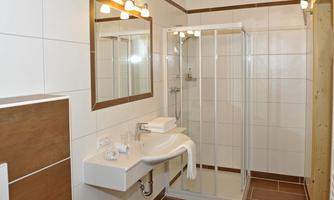 A modern bathroom with a shower and a sink. Bright tiles and a large mirror wall create a friendly atmosphere.