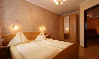 A cozy bedroom with a double bed and soft lighting. The room has a warm hue and a large mirror.