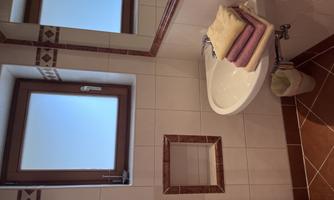 A modern bathroom with a sink and a large mirror. Colorful towels are stacked on the sink.