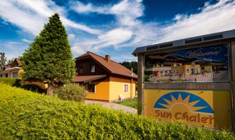 An inviting chalet with colorful facades and a bright blue sky. In the foreground, there is a sign that says "Sun Chalet".