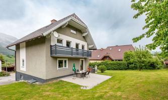 A modern house with a balcony and a terrace in the garden. The green surroundings are inviting and offer plenty of space to relax.