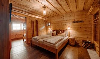 A cozy bedroom with wood paneling and a double bed. The warm wood tones and soft lights create an inviting atmosphere.