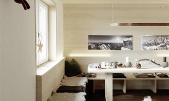 A modern designed room with wood paneling and a large table. Pictures of mountain landscapes hang on the wall, and a trophy mount is decoratively installed.
