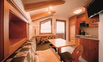 A cozy vacation apartment with wooden details and a seating area. The space is bright and inviting, perfect for relaxing days.