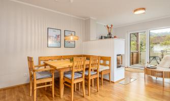 A cozy dining area with a wooden table and chairs. Large windows provide a view outside and ensure plenty of daylight.