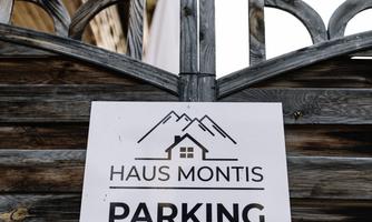 A sign for the parking lot of the Montis house. The design is simple and features mountain silhouettes.