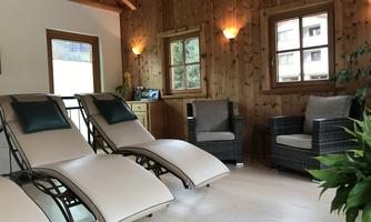 A cozy room with two loungers and an armchair. The walls are made of wood, and daylight is coming in through the windows.