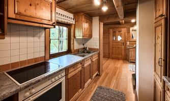 A cozy wooden kitchen with modern appliances and large windows. The floor is made of wood and there is plenty of natural light.