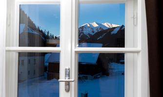 A window view of snow-covered mountains under a clear sky. The landscape conveys a calm winter atmosphere.