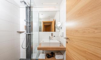 A modern bathroom with a walk-in shower and an elegant sink. The walls are light, and the wooden details give the space a warm atmosphere.
