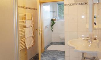 A modern bathroom with striking tiles and a shower. There is a sink and towels, and the light is bright and inviting.