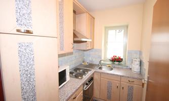 A small kitchen with modern appliances and a window. The walls are bright and the room feels inviting.