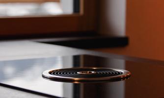 A modern cooking surface with a round cooking zone. The surface is shiny and reflects the light.