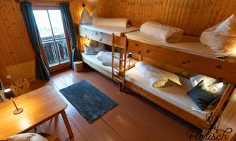 A cozy sleeping area with two bunk beds and a table. The window offers a view outside, the walls are made of wood.