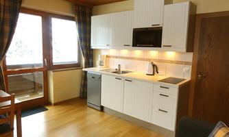A modern kitchen with white cabinets and wood look. Plenty of daylight comes in through large windows.