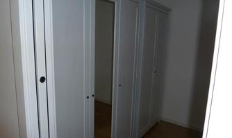 A bright room with white cabinets. The cabinets have simple doors and a wooden floor.