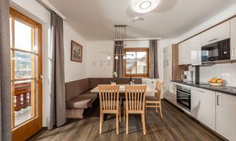 A modern dining room with a wooden table and chairs. The large windows let in plenty of light and offer a view outside.