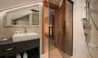 A modern bathroom with a walk-in shower and an elegant sink. The walls are stylishly designed with light tiles.