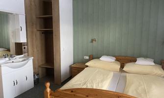 A simple room with two beds and a sink. The room has a calm atmosphere and a wooden ceiling.