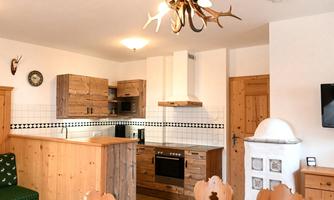A cozy kitchen with wooden furniture and a large dining table. Above the table hangs a striking chandelier made of antlers.