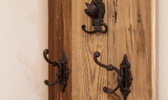 A wooden panel with several decorative black coat hooks. The hooks are artistically designed and stand out against the natural wood.