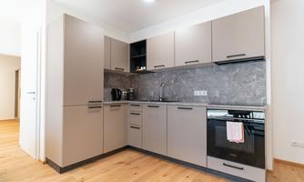A modern kitchen with bright cabinets and modern amenities. The floor is made of wood and the walls are light.