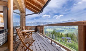 A cozy balcony with wooden loungers and a table offers a breathtaking view of the mountains. The clear air and the panoramic view invite relaxation.
