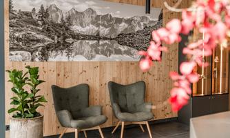 A stylish room with two comfortable armchairs and a large black-and-white photograph of mountains. In the foreground, there are flowers and a plant that add some life to the room.