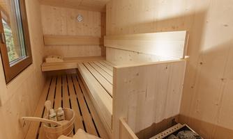 A bright wooden sauna with multiple benches and a stone stove. The walls are made of natural wood, and there is a window that lets in daylight.