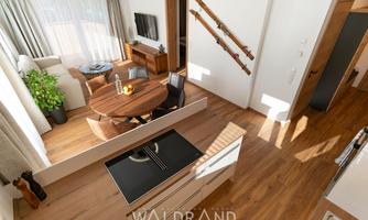 A bright and modern apartment with hardwood floors and elegant interior. The living area is open-plan and features a cozy seating area and a dining table.